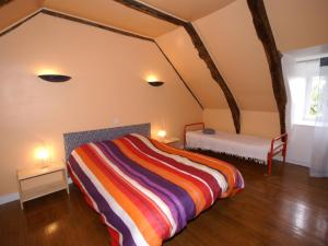 a bedroom with a bed with a colorful striped blanket at Cosy holiday home with garden in Saint-Geniez-dʼOlt