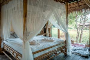 a bedroom with a canopy bed with white drapes at Chai Lai Orchid in Chiang Mai