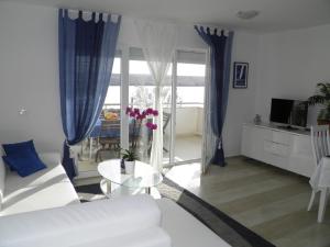 Apartments Perla في Dinjiška: غرفة معيشة مع أريكة بيضاء وطاولة