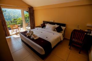 a bedroom with a large bed and a balcony at Edens Munnar in Munnar +37 photos