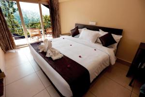 a bedroom with a large bed with a large window at Edens Munnar in Munnar +143 photos