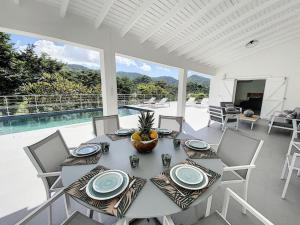 comedor con mesa, sillas y piscina en Villa Jungle Paradise at 5 min from the beach en Friar's Bay