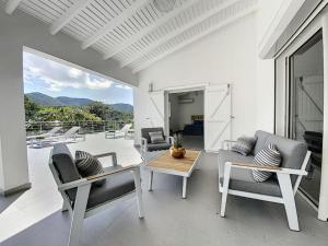 sala de estar con sillas, mesa y balcón en Villa Jungle Paradise at 5 min from the beach en Friar's Bay