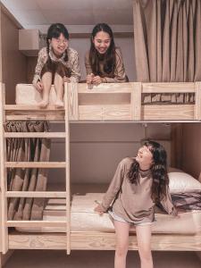 dos chicas sentadas encima de las literas en InnOcean在海裡潛水旅宿 Liuqiu Dive Hostel en Xiaoliuqiu