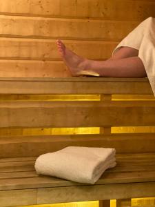una persona sentada en una sauna con los pies sobre una toalla en Strand City Hotel, en Örnsköldsvik