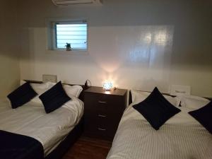 1 dormitorio con 2 camas con almohadas y ventana en Maribu Beach House, en Yamada