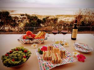 Maribu Beach House في Yamada: طاولة مع كأسين من النبيذ وسندويشات وفواكه