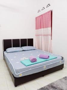 a bed with two towels on top of it at Depulauserai Budget Home No AirCond in Pekan