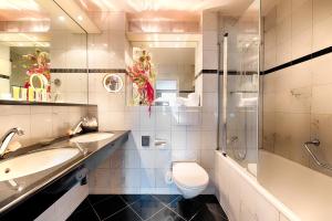 a bathroom with a sink, toilet and bathtub at Lindner Grand Hotel Beau Rivage in Interlaken