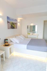 アクロティリにあるアクロテア スイート アンド ヴィラの白いベッドルーム(ベッド1台、鏡付)