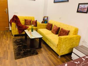 una sala de estar con 2 sofás amarillos y una mesa. en The Influential Square near India Expo Mart en Noida