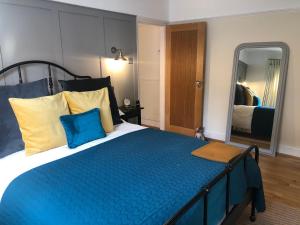 a bedroom with a large blue bed with a mirror at Herons Reach in Budleigh Salterton