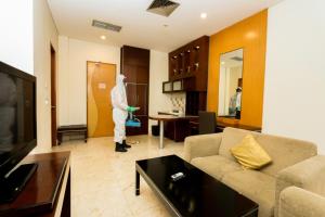 a man in a white suit standing in a living room at Serela Riau by KAGUM Hotels in Bandung