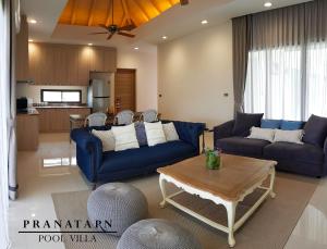 a living room with blue couches and a table at Pranatarn Pool Villa Beach Night Cottage in Pran Buri