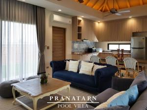 a living room with a blue couch and a kitchen at Pranatarn Pool Villa Beach Night Cottage in Pran Buri