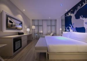 a bedroom with a large white bed and a tv at Orange hotel select (shanghai pudong Airport Hotel) in Shanghai
