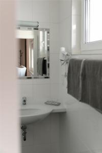 uma casa de banho branca com um lavatório e um espelho em KRACHER Guesthouse No 3 em Illmitz