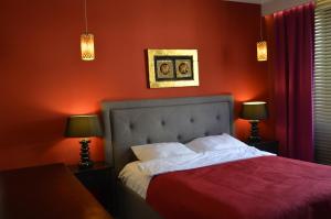 a bedroom with a bed with red walls and two lamps at Apartamenty Dream of Bydgoszcz in Bydgoszcz