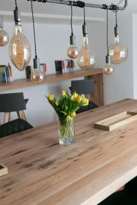 a vase of flowers on a wooden table with lights at KRACHER Ferienhaus No 2 in Illmitz