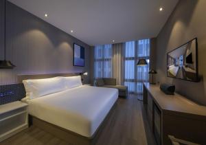 a bedroom with a large white bed and a television at Orange hotel select (shanghai pudong Airport Hotel) in Shanghai