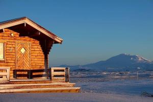 eine Holzhütte mit einem Zaun und Bergen im Hintergrund in der Unterkunft Guesthouse Didi in Flagbjarnarholt
