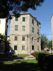 a man walking past a stone building with green windows at Studio Apartment Sretna in Split