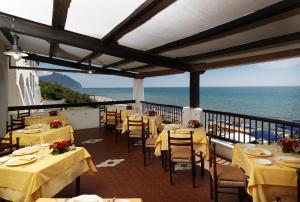 een restaurant met tafels en stoelen en uitzicht op de oceaan bij Hotel Le Dune in Sabaudia