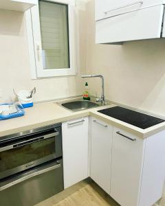 uma cozinha com armários brancos e um lavatório em Villa Antioco em Cala Sapone