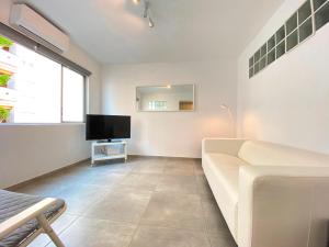 een woonkamer met een witte bank en een tv bij Cap Negret 30 in Altea
