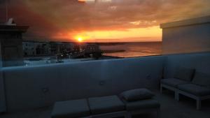 ポリニャーノ・ア・マーレにあるFONTEblu B&Bのソファ付きの客室から夕日の景色を望めます。