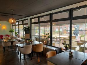 un restaurante con mesas, sillas y ventanas grandes en Hotel Restaurant Anno Nu, en Oostkapelle