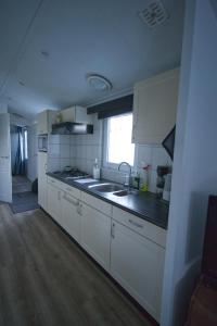 a kitchen with white cabinets and a sink and a window at chalet hensbroek in Hensbroek