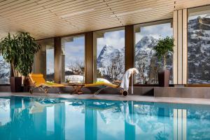 a resort with a swimming pool and mountains at Eiger Mürren Swiss Quality Hotel in Mürren