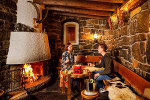 a man and a woman sitting at a table next to a fireplace at Eiger Mürren Swiss Quality Hotel in Mürren