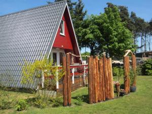 une grange rouge avec une clôture devant elle dans l'établissement Finnhütte Rabennest, à Freest
