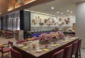 a dining room with a long table with flowers on it at Vivanta Kolkata EM Bypass in Kolkata