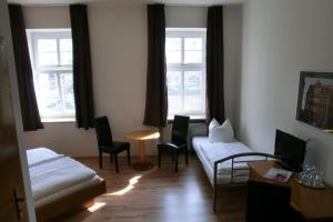 a living room with a bed and chairs and windows at Hotel Schweizer Hof in Halle an der Saale