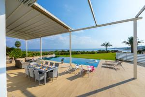 Un patio con mesa y sillas y una piscina. en Infinity Villa, en Protaras