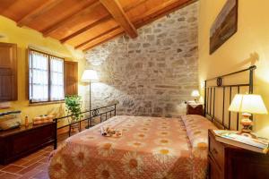 1 dormitorio con cama y pared de piedra en Gilda, en Roccalbegna
