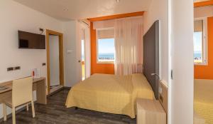una camera d'albergo con due letti, una scrivania e una finestra di Hotel Villa Gioiosa a Lido di Jesolo