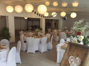 - une salle de banquet avec des tables blanches, des chaises et des lumières dans l'établissement Domaine de la Palle, à Pontgibaud