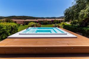 - une piscine sur une terrasse en bois à côté d'une cour dans l'établissement Hotel Costa Caddu, à San Teodoro