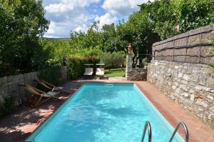 uma piscina num quintal com uma parede de pedra em Ciacchieri em Gaiole in Chianti