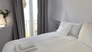 a white bed with white pillows and a window at Hotel Boutique Suite Generis, Premiado El hotel más acogedor de España in Córdoba