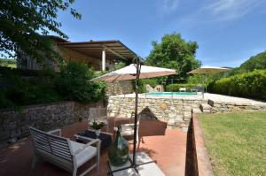 un patio con 2 sillas, una sombrilla y una piscina en Capanna di Camporata, en Gaiole in Chianti