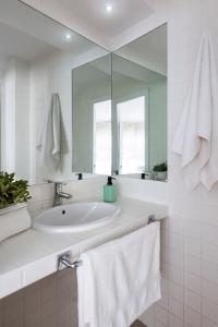 a bathroom with a sink and a mirror and towels at AlohaMundi San Luis in Seville