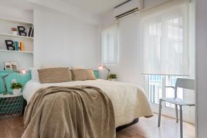 a white bedroom with a bed and a chair at AlohaMundi San Luis in Seville
