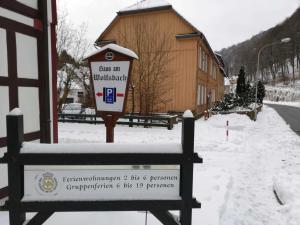 un cartello nella neve davanti a un edificio di Haus am Wolfsbach Gruppenunterkunft a Zorge