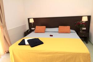 Una cama amarilla con almohadas naranjas y negras. en Club Esse Sunbeach, en Squillace