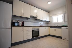 uma cozinha com armários brancos e um forno com placa de fogão em Casa Riu Avall em Riumar